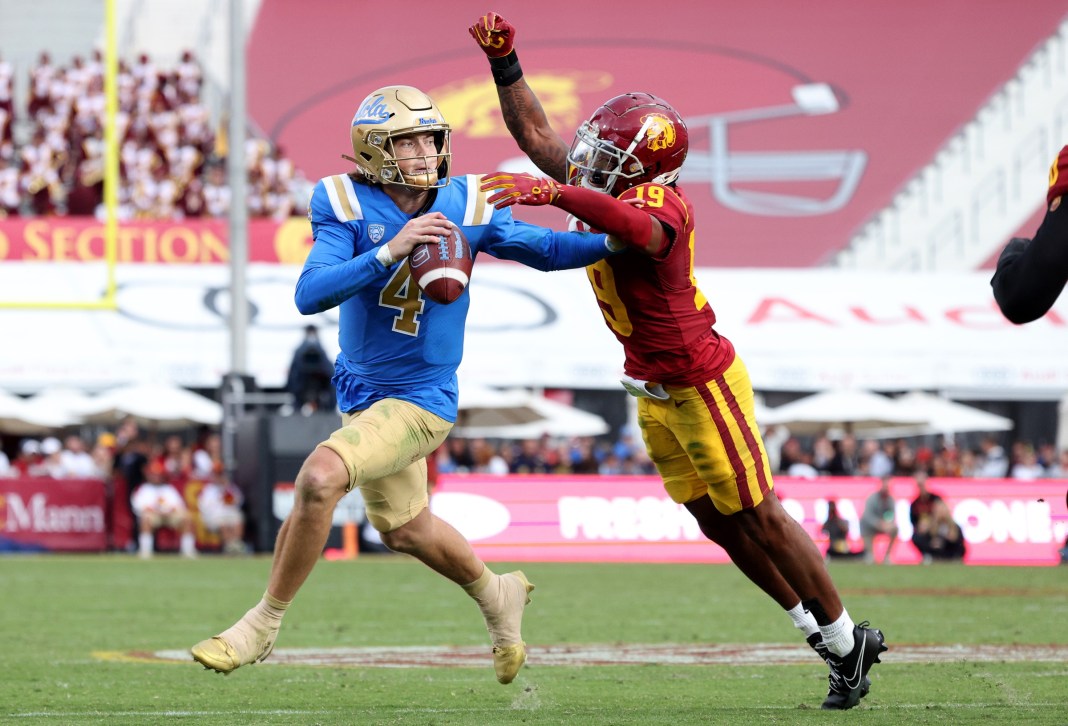 UCLA Bruins quarterback Ethan Garbers (4) scrambles to throw a touchdown under pressure from USC Trojans safety Jaylin Smith (19) during the third quarter at United Airlines Field at Los Angeles Memorial Coliseum on November 18, 2023.