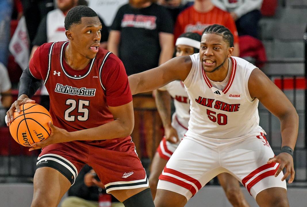 New Mexico State's Emmanuel Tshimanga looks for an open pass as Jax State's Mason Nicholson defends during college basketball action in Jacksonville, Alabama, on February 20, 2025. Jax State fell to New Mexico State 61-52.