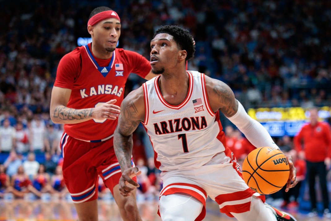 Arizona Wildcats guard Caleb Love (1) drives to the basket around Kansas Jayhawks guard Dajuan Harris Jr. (3) during the first half at Allen Fieldhouse on March 8, 2025.